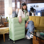 Woman with a Cloud Large Check-In - In Apple Green suitcase in a modern living room