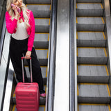 Woman in pink jacket and black pants with a Tesport Cloud Collection pink suitcase on an escalator