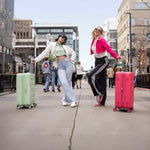 Two women with colorful Tesport Cloud Collection suitcases walking on a city street.