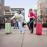 Two women with colorful Tesport Cloud Collection suitcases walking on a city street.
